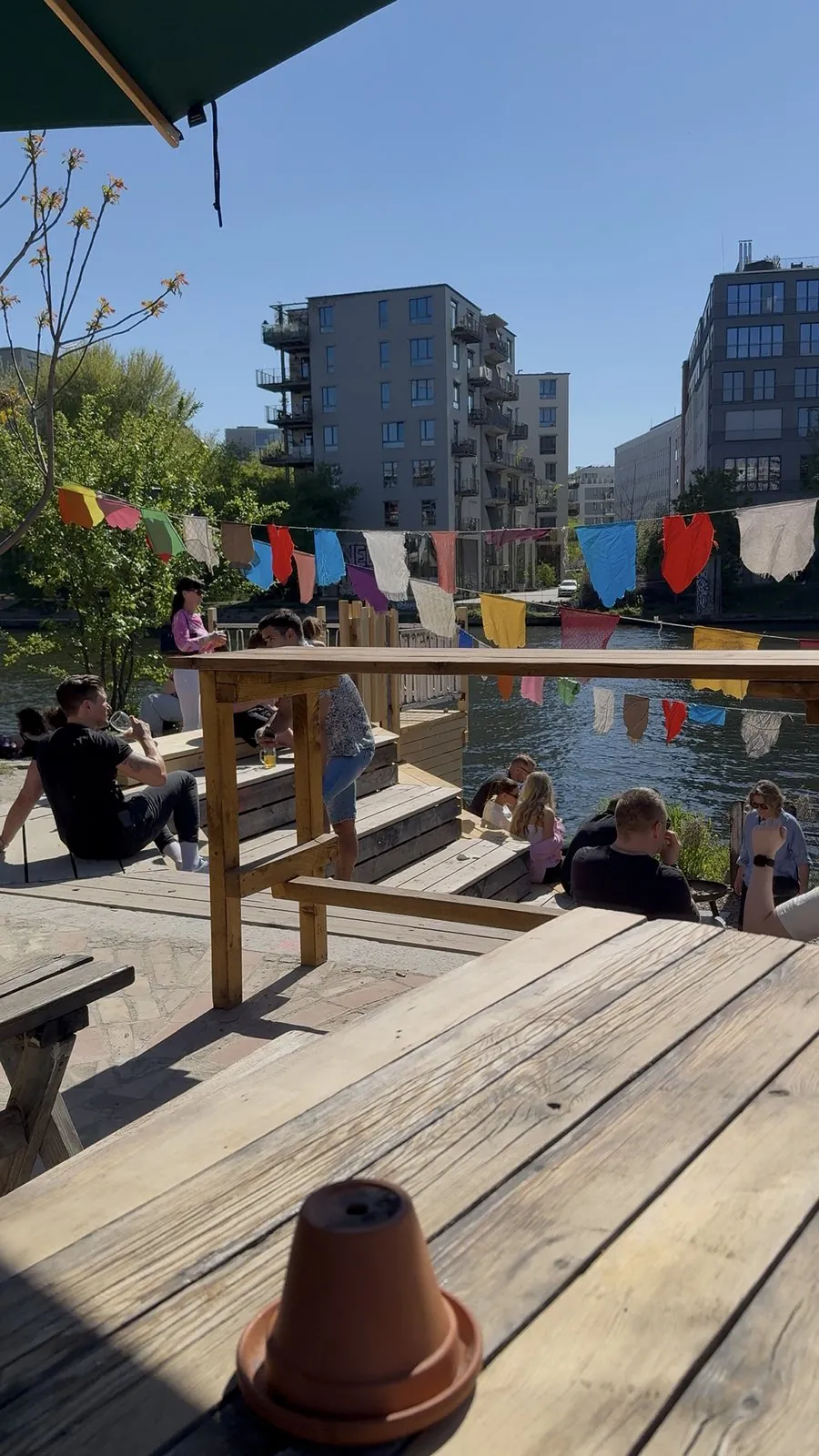 A Berlin Biergarten on the canal — long shared tables, families, the city's outdoor sociability the moment the sun returns