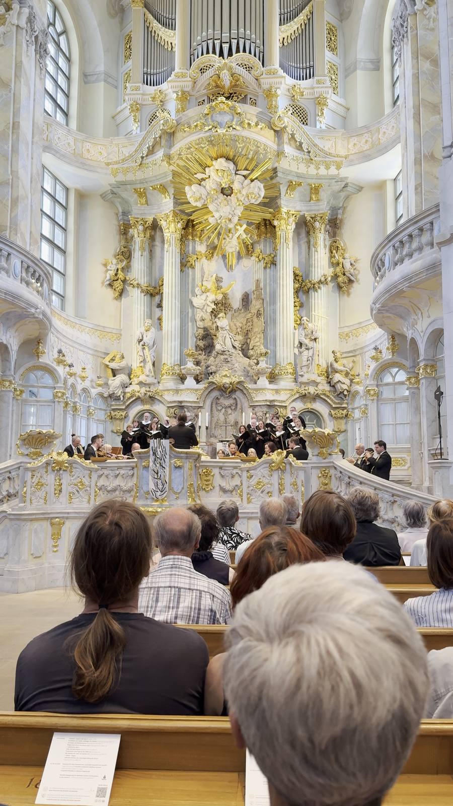 A choral concert beneath the gilded altar of the Frauenkirche, Dresden, seen from the pews