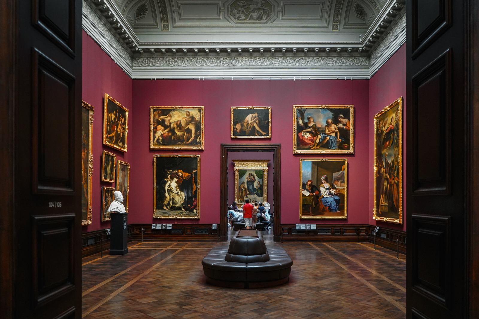 A red-walled room of the Old Masters Picture Gallery in Dresden, hung with Italian paintings