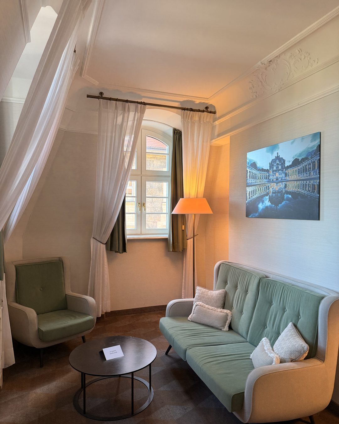 A guest room at the Gewandhaus Dresden, with a sage-green sofa and tall windows