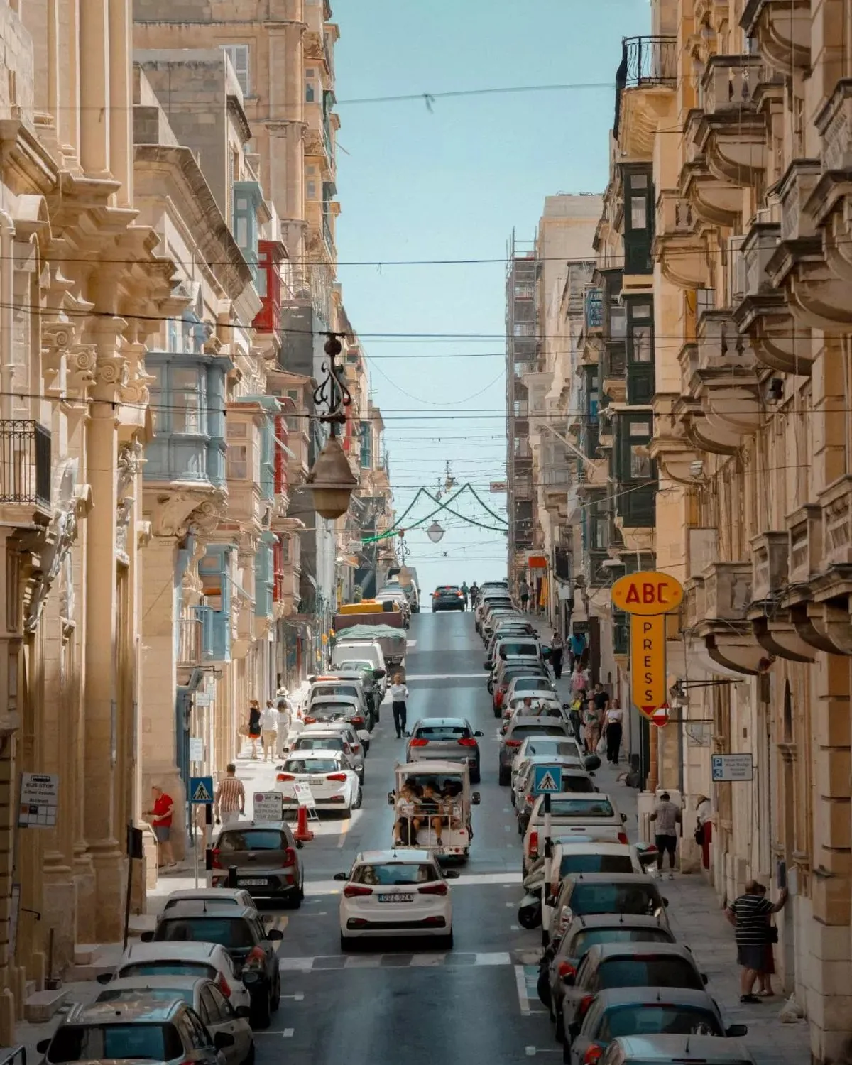 Narrow uphill street in Valletta with traditional Maltese balconies